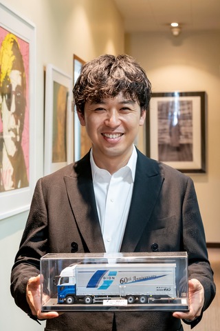 ギオンは2025年に創業60周年を迎えた。記念に製作されたトラックのプラモデルを手にする須藤氏